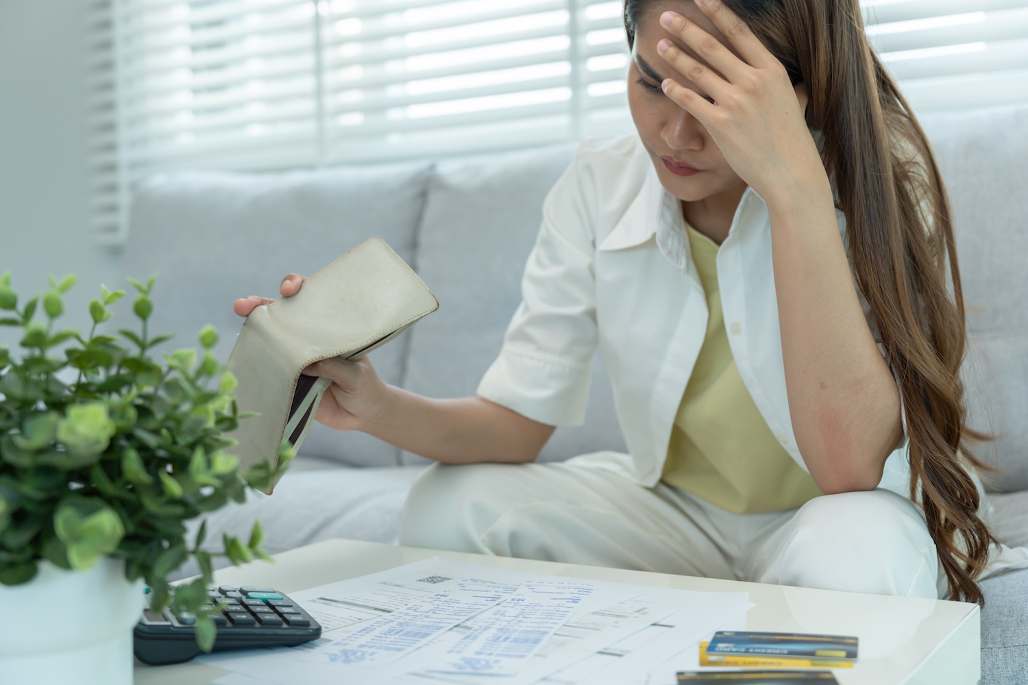 Woman looking at her bills and credit cards to represent owing debts to Pastdue Credit Solutions.