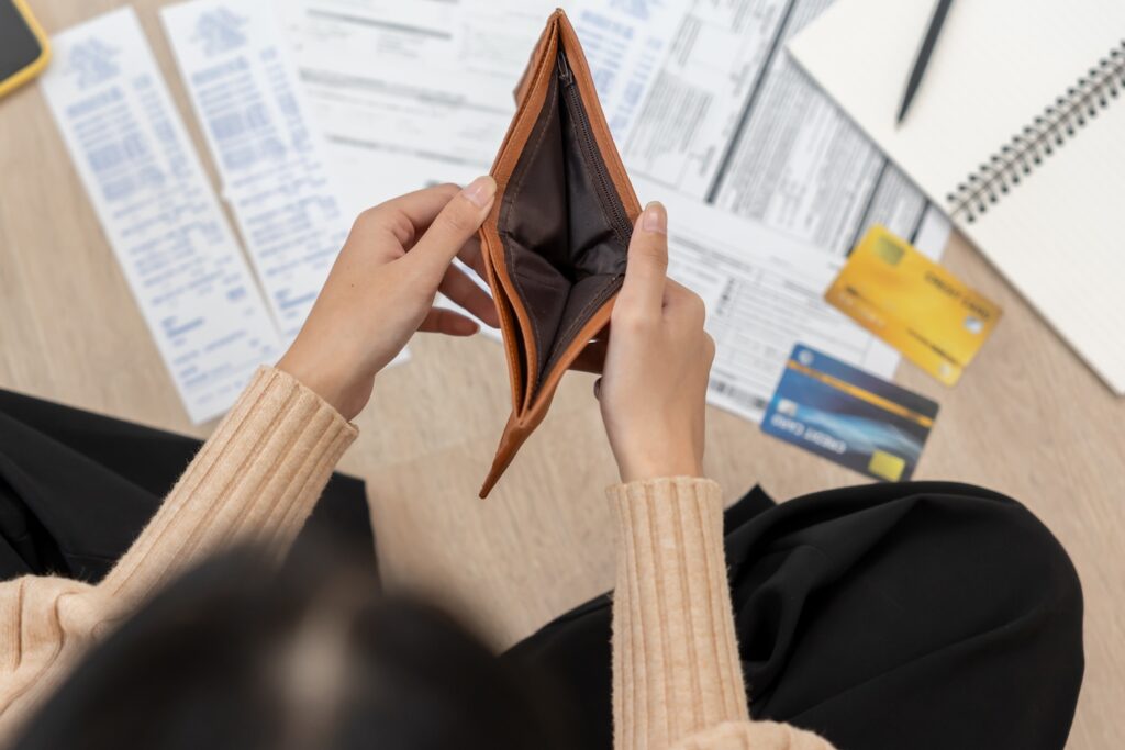 Woman with bills and an empty wallet wondering how often do debt collectors take you to court