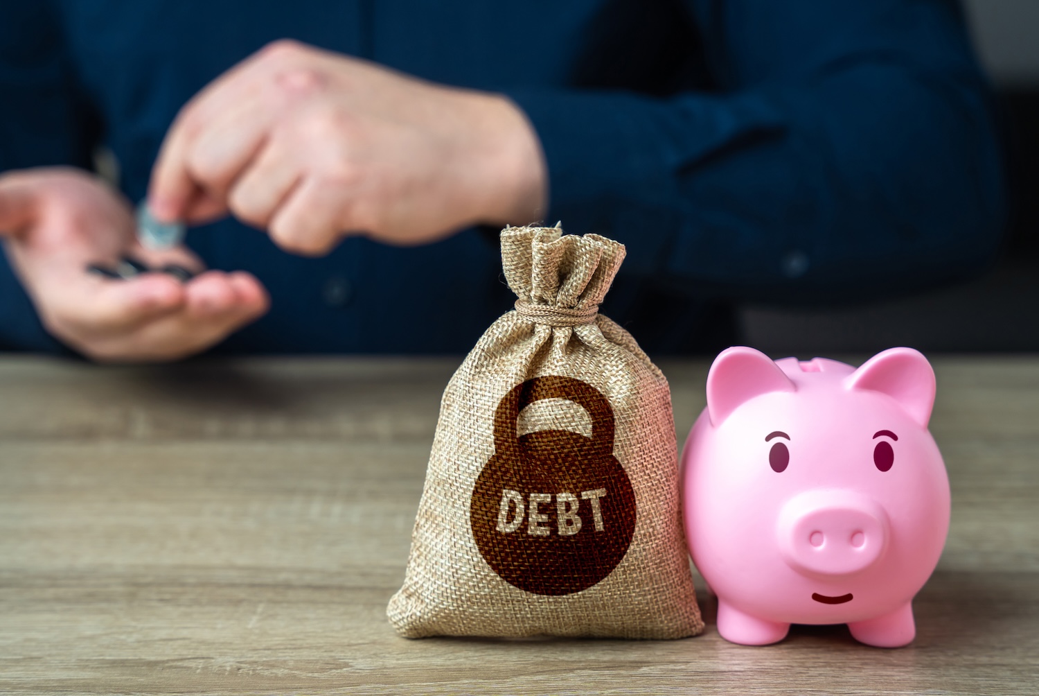 Man counting coins with piggy band and a bag labelled debt to illustrate secured loans debt
