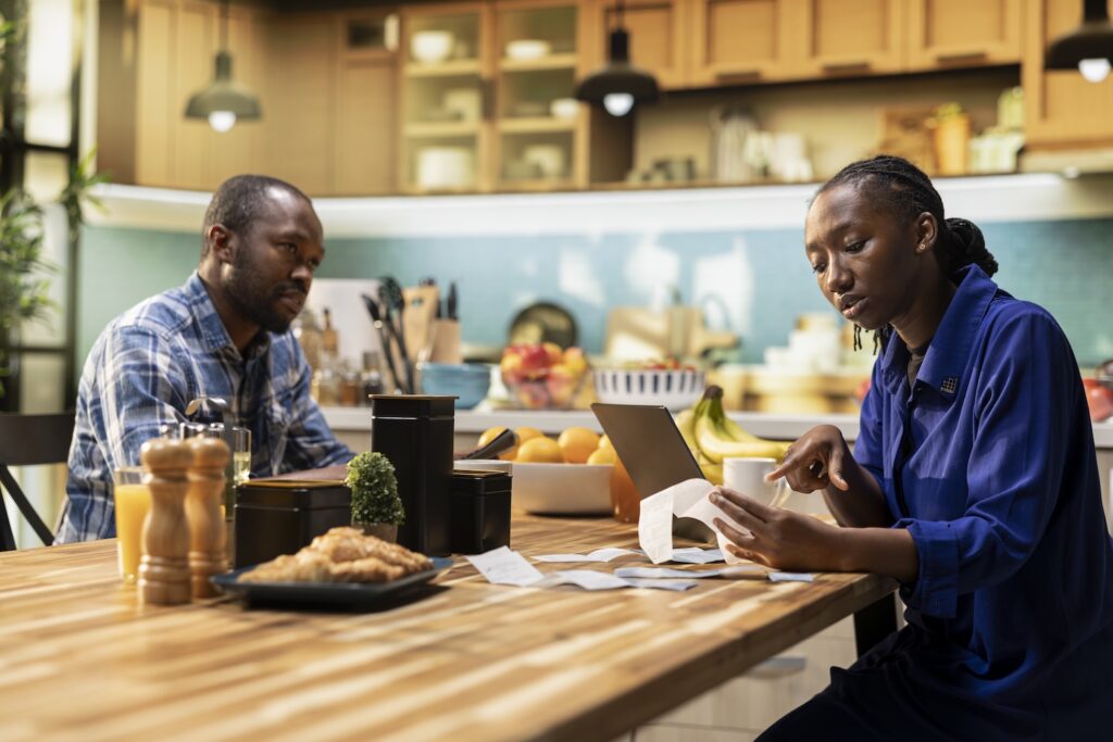 Couple sat at kitchen table reviewing expenses asking can debt be written off?