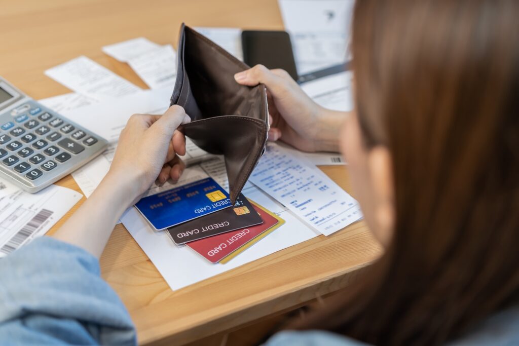A stressed woman looking at her credit cards, bills and empty wallet wondering if she can have an iva twice
